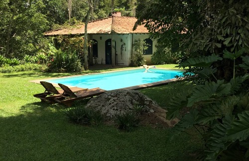 Correas House | Colonial house with a smaller house on the edge of a river and along the forest.