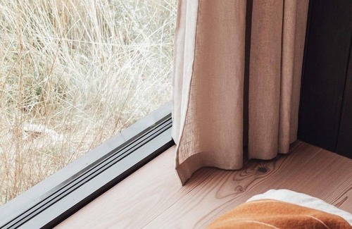 Wilsum Cabin | The Nokken Forest Cabin stands on the edge of the forest with unobstructed views over a rolling landscape. This cabin offers a lot of privacy due to its location. The large window is facing west. Enjoy the sunset over an endless cornfield from your b