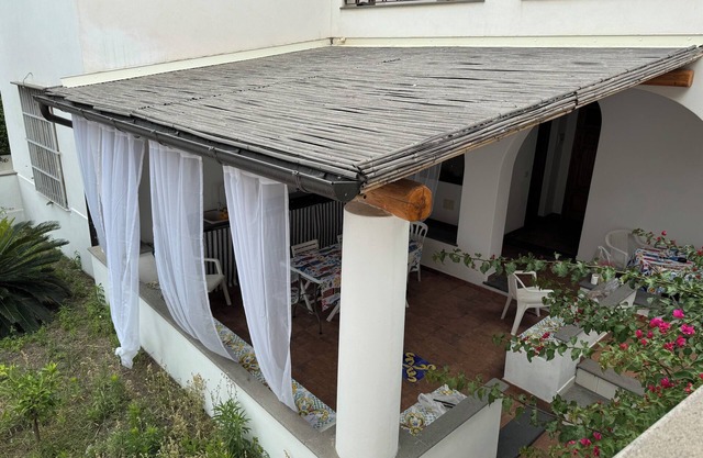 Villa with patio surrounded by greenery, equipped kitchen on the patio. Close to the sea